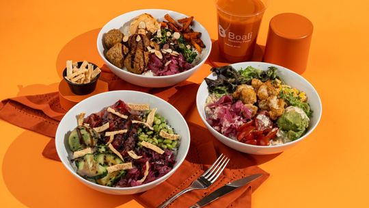Three Boali bowls with a fresh juice on an orange table
